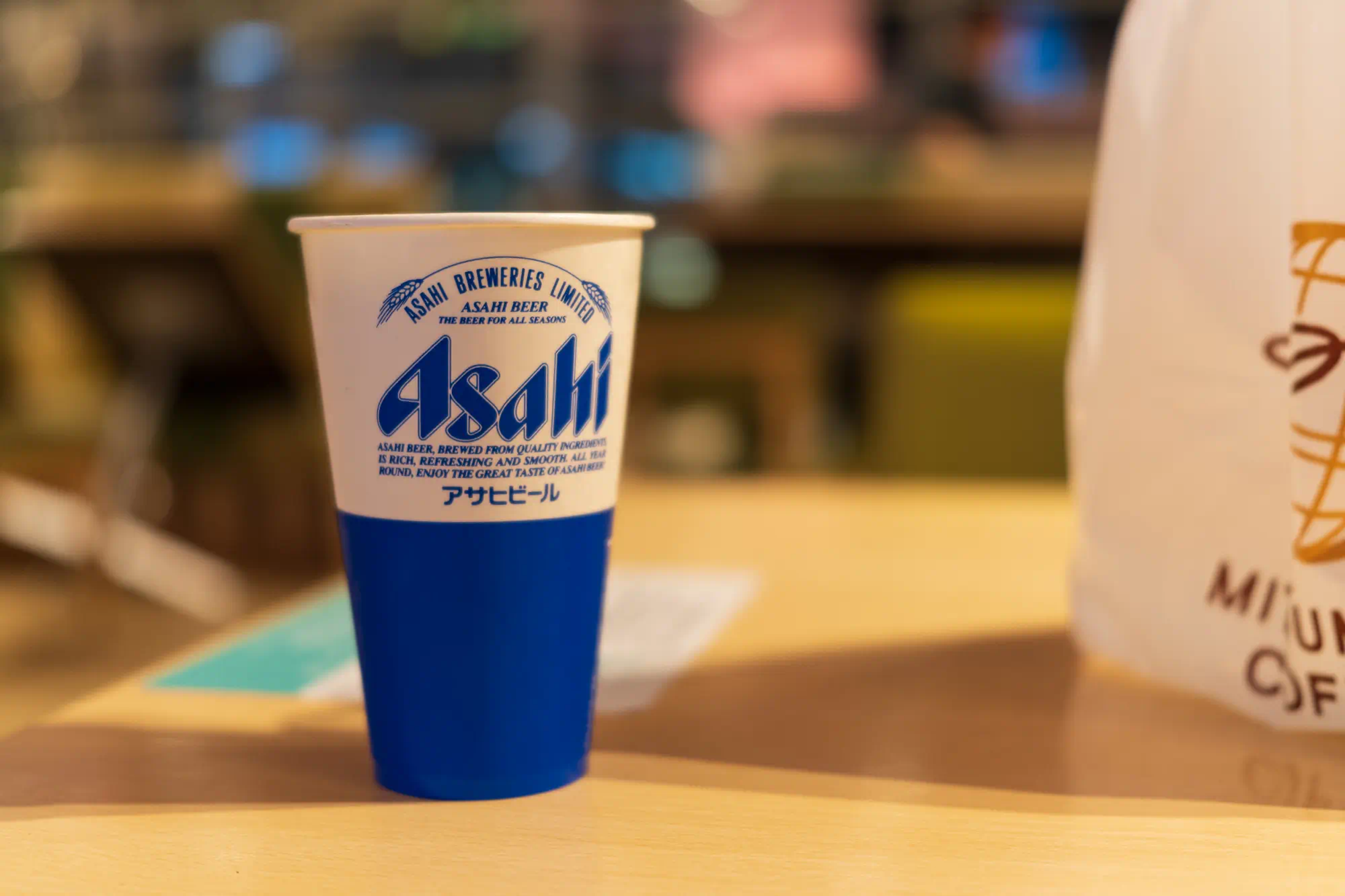 Asahiとロゴの入った青い紙カップがテーブルの上にある