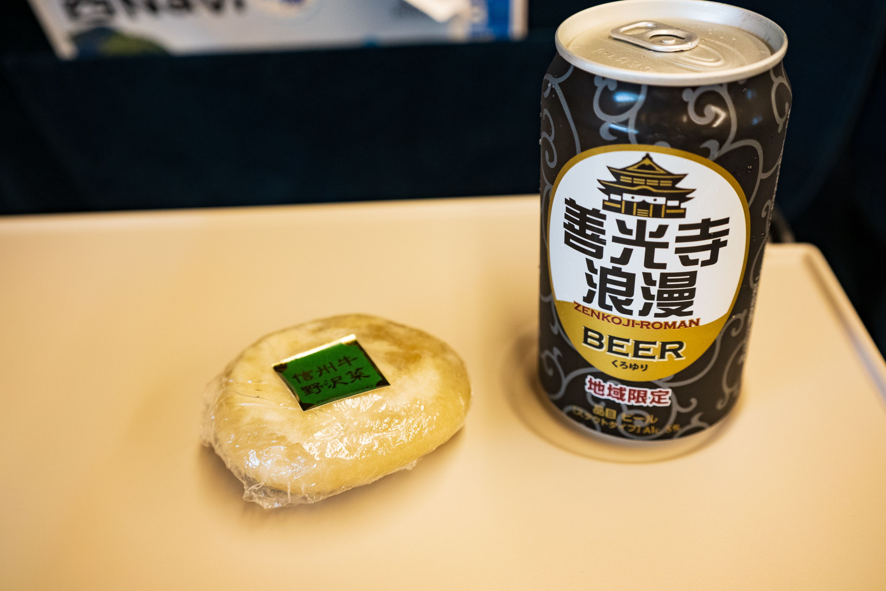 おやきとビールが新幹線のテーブルに乗っている