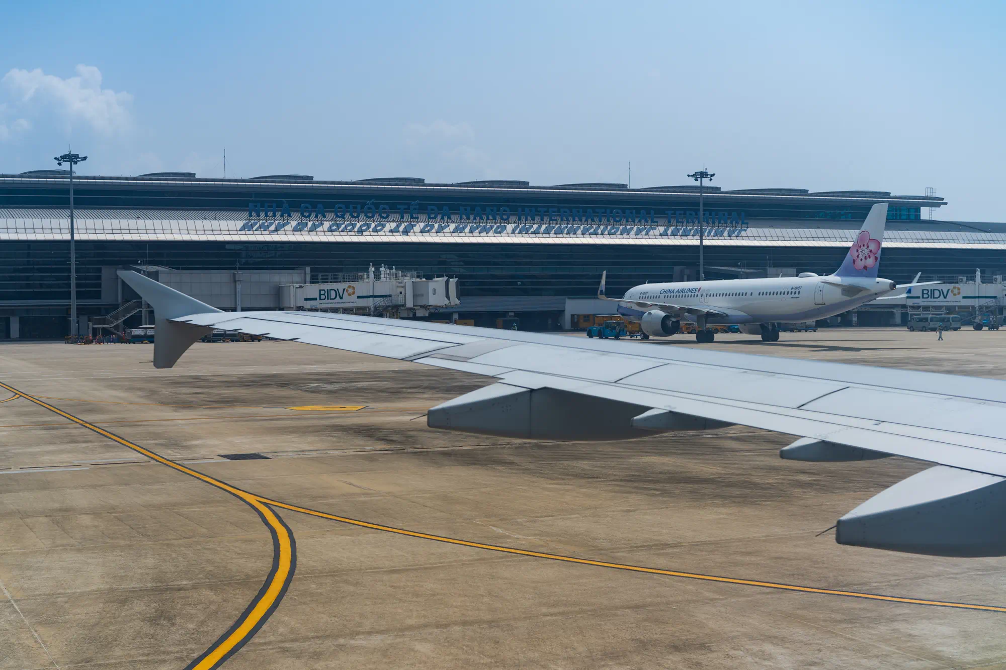 ダナン到着時の機内からの光景。翼とダナン国際空港のターミナル、空港名の看板が見える。