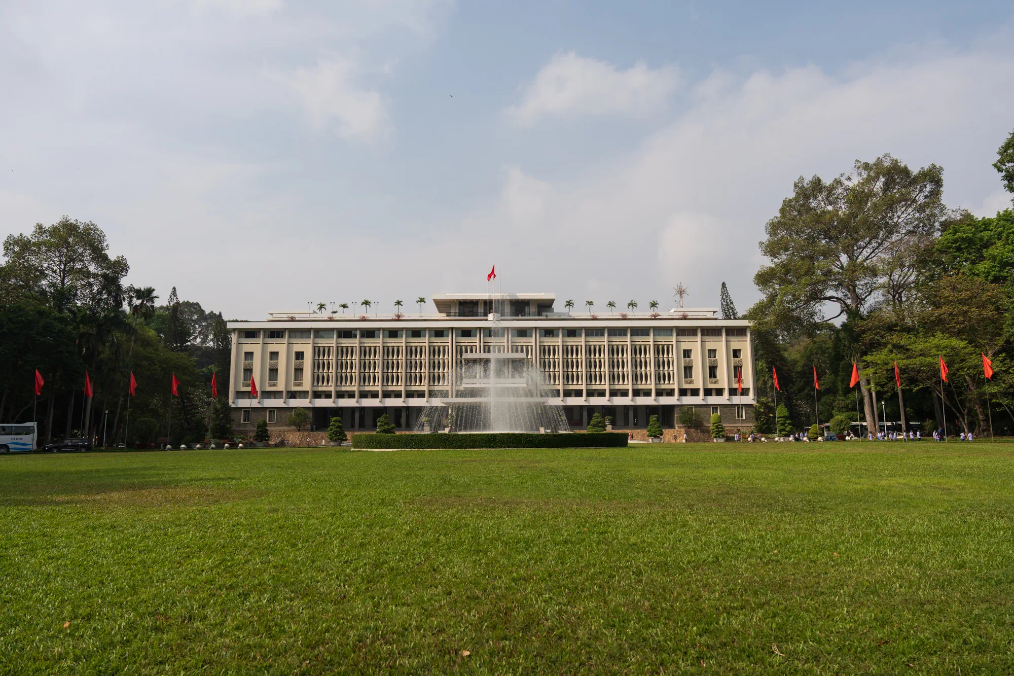統一会堂外観。広い芝生、噴水、大きな建物、ベトナム国旗