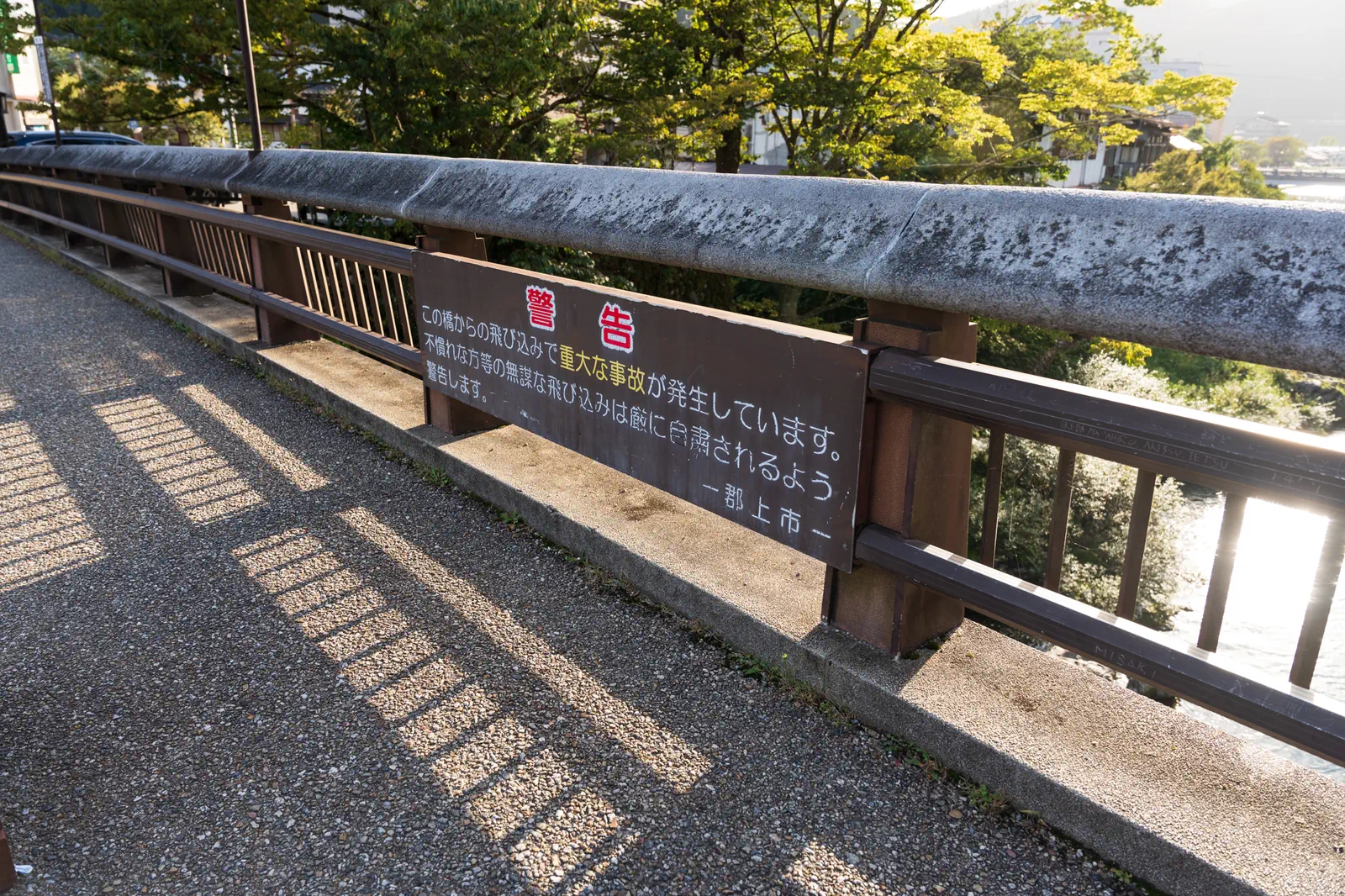 橋の欄干に看板があり、「不慣れな方等の無謀な飛び込みは厳に自粛されるよう警告します」とある