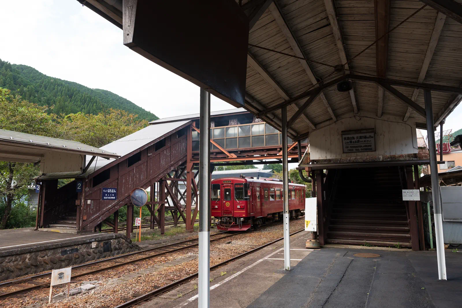 郡上八幡駅構内。木造の跨線橋が古い。発車する赤い列車が見える