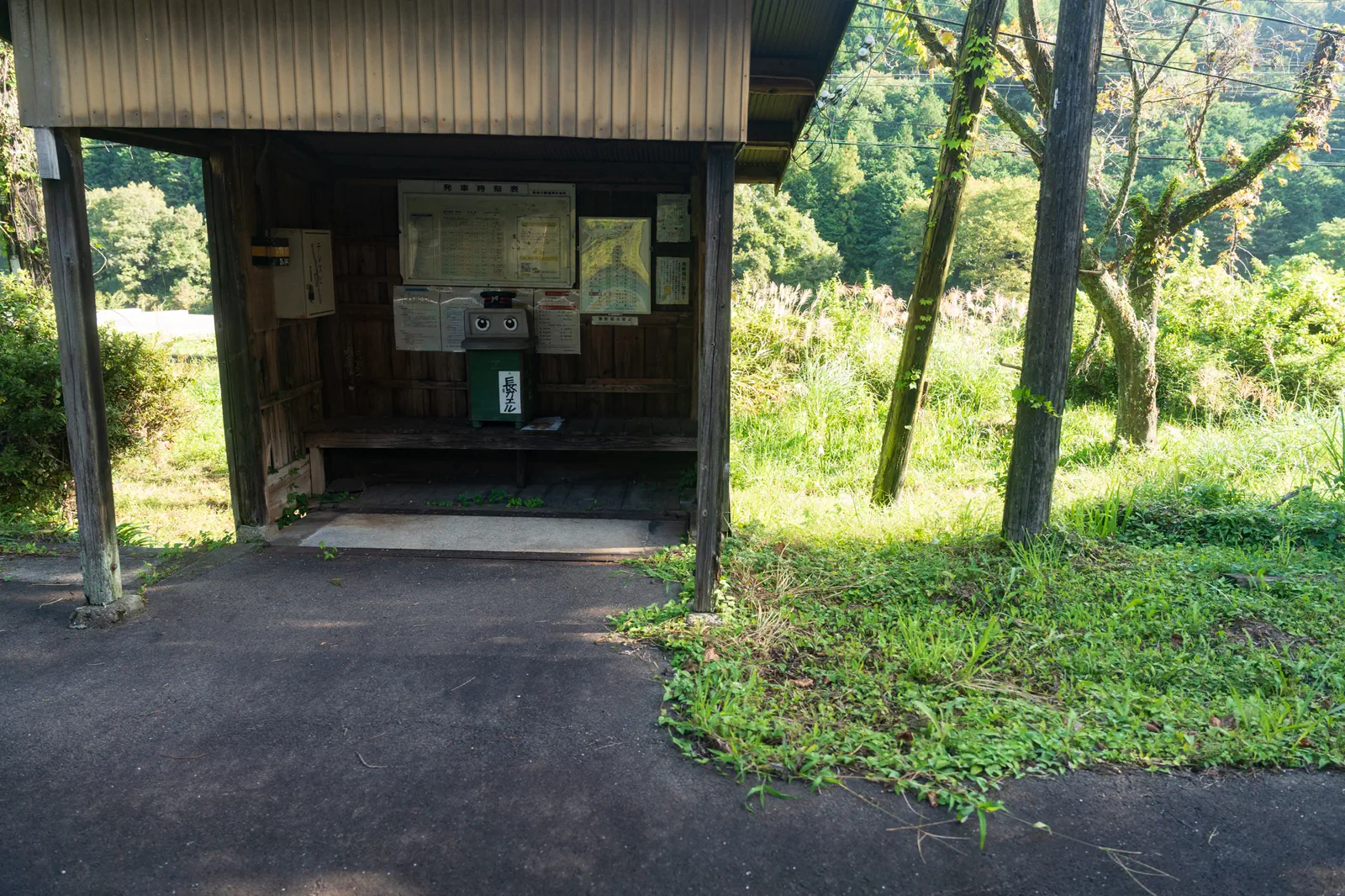 駅の待合所になっている小さい小屋と、そこに置かれている緑色のゴミ箱（目がかいてあり、長カエルという名札がついている